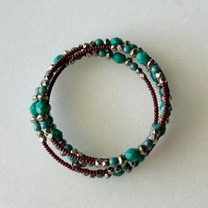 May include: A multi-strand bracelet with turquoise and brown beads. The bracelet is made of multiple strands of beads that are woven together.