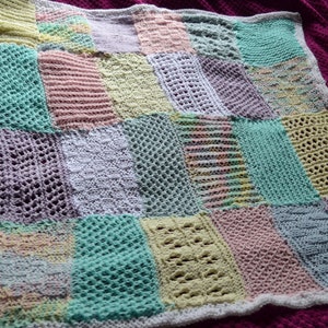 May include: A crocheted baby blanket with a patchwork design in shades of pink, green, white, and yellow.