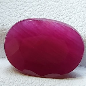 Puede incluir: Una piedra preciosa ovalada lisa de color rosa con un sutil patrón estriado.