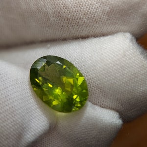 Peut inclure: Une pierre pr&eacute;cieuse ovale de couleur verte avec une taille facet&eacute;e. La pierre est translucide et a une l&eacute;g&egrave;re teinte jaune.
