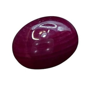 May include: A deep red oval gemstone with a smooth, polished surface.