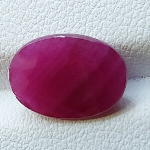 May include: A vibrant pink oval gemstone with a smooth, polished surface.