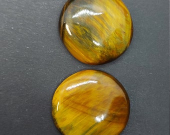 Peut inclure: Deux cabochons ronds en œil de tigre poli. Les pierres sont un mélange de brun doré et de noir avec un effet chatoyant.