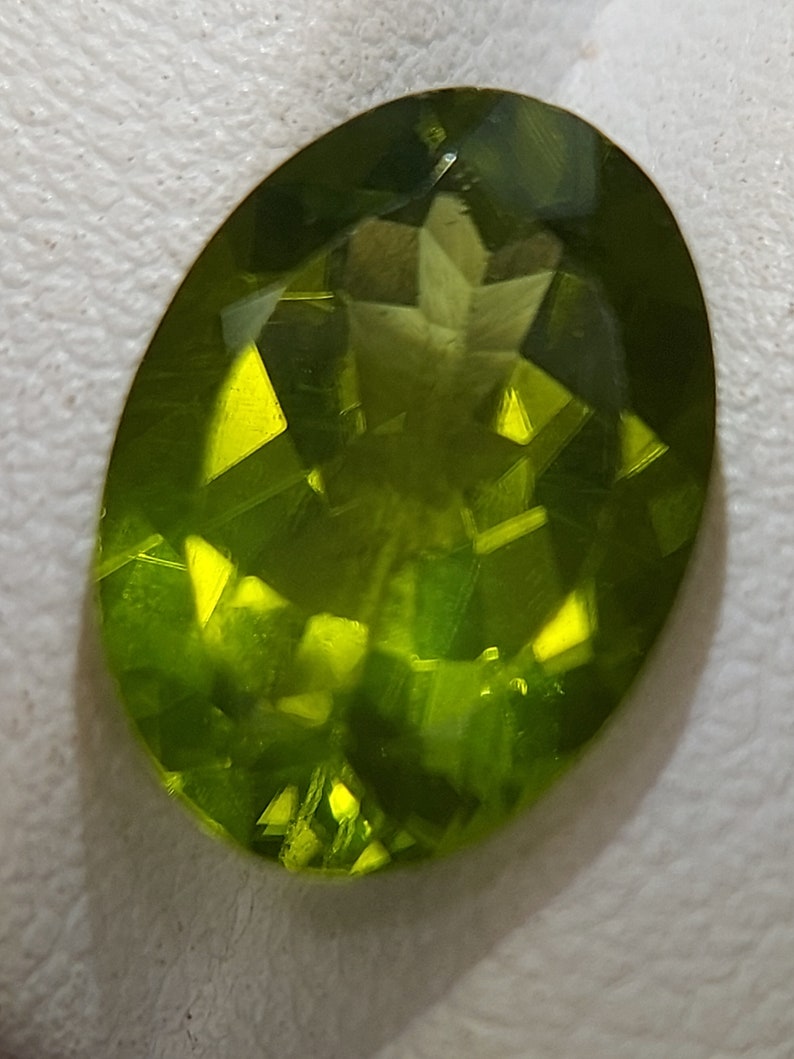Peut inclure: Une pierre pr&eacute;cieuse verte taill&eacute;e &agrave; facettes. La pierre pr&eacute;cieuse est de forme ovale et a une finition brillante.