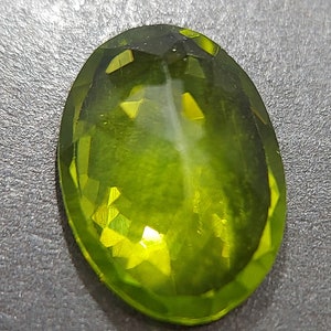 Peut inclure: Gros plan sur le dos d'une pierre pr&eacute;cieuse verte. La pierre est de forme ovale et a une taille facet&eacute;e. La pierre r&eacute;fl&eacute;chit la lumi&egrave;re, cr&eacute;ant un effet brillant et lumineux.