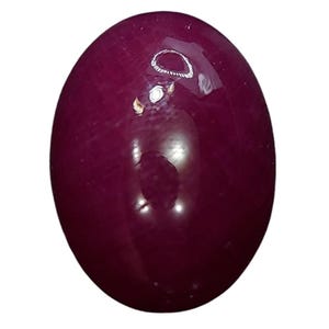 May include: A polished, oval gemstone in a deep burgundy colour. The surface reflects light, creating highlights. The gemstone is likely for jewellery making or collection.