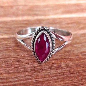 Op de afbeelding: Een zilveren ring met een marquise-vormige robijn-edelsteen gezet in een gedraaide zilveren band.