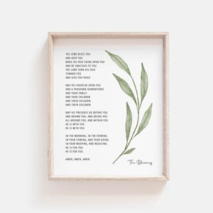 Op de afbeelding: Een printbaar wandkunstontwerp met een aquarel-illustratie van een bebladerde tak. De tekst luidt: "De Heer zegene u en bewaar u. Laat zijn aangezicht over u schijnen en wees u genadig. De Heer wende zijn aangezicht naar u en geef u vrede. Moge zijn gunst over u en over duizend generaties zijn, over uw gezin, over uw kinderen, over hun kinderen en over hun kinderen. Moge zijn aanwezigheid voor u uitgaan en achter u aan, zij zij aan uw zijde, zij omhulle u en zij in u zijn. Hij is met u. Hij is met u. In de ochtend, in de avond, bij uw komen en gaan, in uw tranen en in uw vreugde, hij is voor u. Hij is voor u. Amen, Amen, Amen. De Zegen."