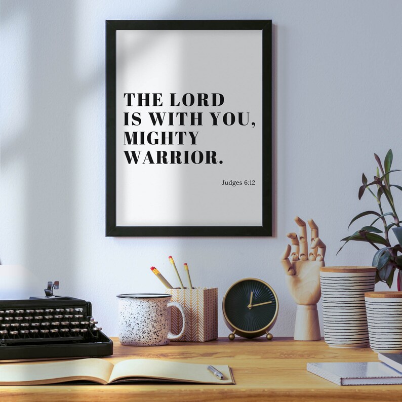 Pu&ograve; includere: Stampa incorniciata in bianco e nero con il testo "The Lord is with you, mighty warrior." e il riferimento biblico "Judges 6:12".