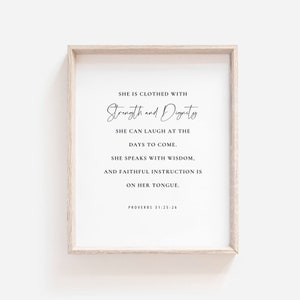 Può includere: Un design di arte da parete stampabile con una cornice in legno beige. Il testo recita "Ella è vestita di forza e dignità. Può ridere dei giorni a venire. Parla con saggezza, e l'istruzione fedele è sulla sua lingua. Proverbi 31:25-26"