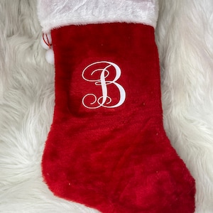 May include: Red Christmas stocking with a white fluffy cuff and a white monogram of the letter "B" on the front.
