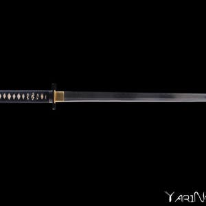 Pode incluir: Uma katana, uma espada japonesa, com uma empunhadura preta e uma lâmina prateada. A empunhadura tem um padrão de losangos. A espada está sobre um fundo preto.