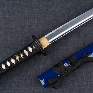 May include: A traditional Japanese katana sword with a black and white patterned handle and a blue scabbard.