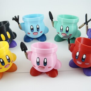 May include: Seven colorful ceramic planters shaped like a cartoon character with different gardening tools. The planters are in the colors blue, green, black, yellow, pink, and red.