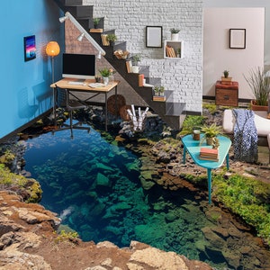 Puede incluir: Una calcomanía de suelo 3D que representa una laguna azul con rocas y plantas verdes. La calcomanía se coloca en una habitación con una pared de ladrillo blanco, una escalera de madera y una pared azul.