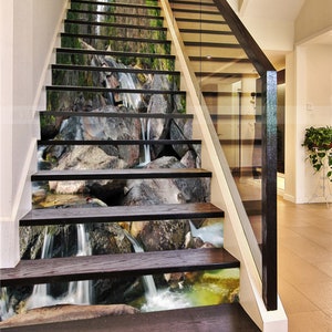 May include: A set of stair treads with a waterfall and rocks design. The treads are made of wood and have a realistic image of a waterfall and rocks printed on them.