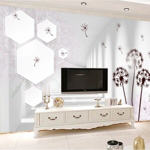 May include: White wall with a geometric pattern of hexagons and a white and grey floral design. The wall has a flat screen TV mounted on it and a white dresser with three drawers. The wall is decorated with black dandelion silhouettes.