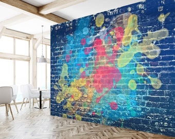 May include: A blue brick wall with colourful paint splatters in shades of yellow, blue, pink, and green. The paint splatters are abstract and create a modern, artistic design.