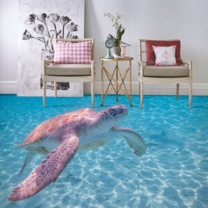 May include: A sea turtle swims in a blue and white ocean floor design. The floor design is a 3D effect that makes it look like the turtle is swimming in a real ocean. The floor design is in a living room with two chairs and a table.