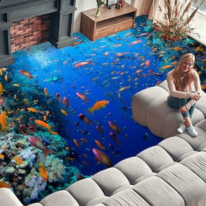 Puede incluir: Un sofá seccional blanco con una escena submarina azul y naranja impresa en el suelo. La escena presenta arrecifes de coral, peces y un buceador.