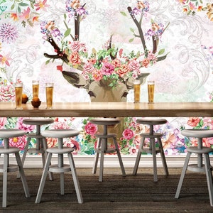 Peut inclure: Un fond blanc avec un motif floral et un cerf aux bois ornés de fleurs. Quatre tabourets de bar blancs sont disposés devant une table en bois.