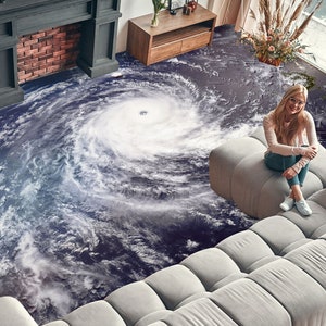 Peut inclure: Une femme est assise sur un canapé modulable blanc avec un motif d'ouragan bleu et blanc sur le sol. Le canapé est composé de coussins individuels et a un design moderne.