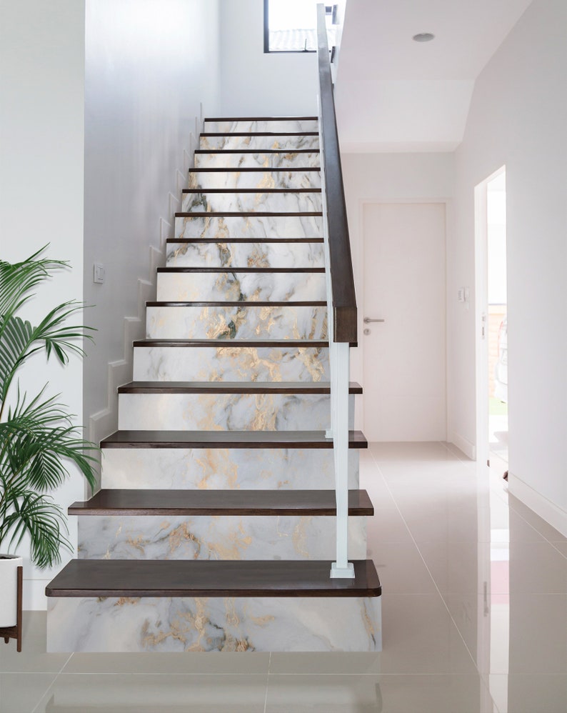 May include: White and gold marble-patterned stair treads with dark brown wood risers. The stairs are in a modern home with white walls and a white railing.