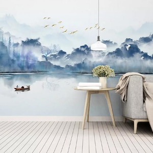 May include: A watercolour painting depicting a misty mountain landscape with a lake in the foreground. A small boat with a person in it is on the lake. The painting is in shades of blue and grey, with hints of gold.