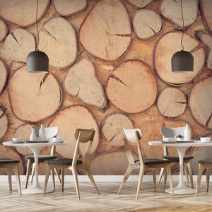 Può includere: Una sala da pranzo con una carta da parati effetto legno che presenta un motivo di anelli di alberi impilati. La stanza ha un tavolo bianco con quattro sedie, due luci a sospensione e una pianta sul tavolo.