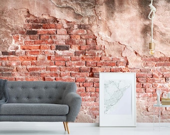 May include: A grey sofa with button tufting sits in front of a brick wall with distressed plaster. A white frame with a black and white map print hangs on the wall. A hanging light fixture with a gold bulb hangs from the ceiling.