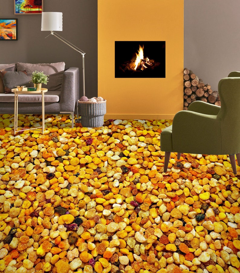 May include: A close-up of a patterned floor covering that looks like a pile of small, yellow, orange, and brown pebbles. The floor is in a living room with a couch, a lamp, and a fireplace.
