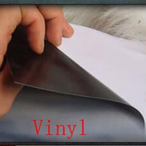 May include: A close-up of a vinyl sticker being peeled off of its backing paper. The sticker is black and has the word "Vinyl" printed in red.