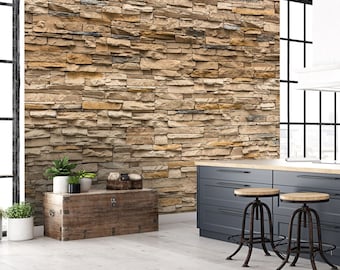 May include: A rustic wooden storage chest with a distressed finish sits in front of a wall covered in a faux stone wallpaper. The wallpaper features a variety of brown, beige, and gray stones arranged in a random pattern. Two black metal bar stools with brown leather seats are in the foreground.