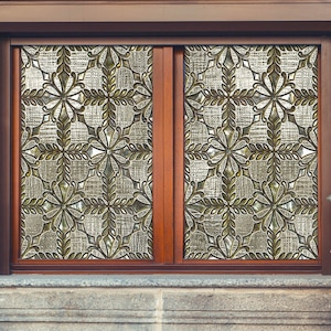 May include: A window with a decorative glass pane featuring a geometric pattern of overlapping circles and leaves. The glass is a light brown color and the window frame is a dark brown wood.