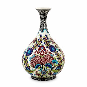 Op de afbeelding: Een keramische vaas met een smalle hals en een bolvormig lichaam, voorzien van een witte basis versierd met ingewikkelde bloemmotieven in rood-, blauw- en groentinten. De hals en voet zijn geaccentueerd met een gedetailleerd zwart-wit krulpatroon.
