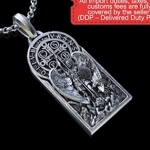 May include: A silver pendant necklace featuring a detailed religious design. The pendant has an engraved image of a saint with wings, holding a cross and shield. The necklace includes a chain and the text "No surprise fees, taxes, or duties at delivery."