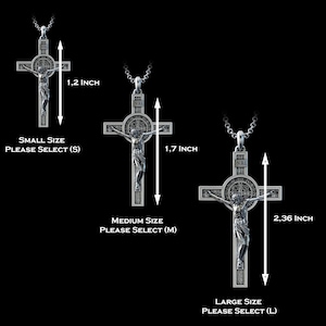 K&ouml;nnte beinhalten: Drei silberfarbene Kruzifix-Anh&auml;nger mit einer zentralen Jesusfigur und einer runden Benediktusmedaille. Die Gr&ouml;&szlig;en sind mit 3,05 cm f&uuml;r klein, 4,32 cm f&uuml;r mittel und 5,99 cm f&uuml;r gro&szlig; angegeben, inklusive Text f&uuml;r die jeweilige Auswahl.