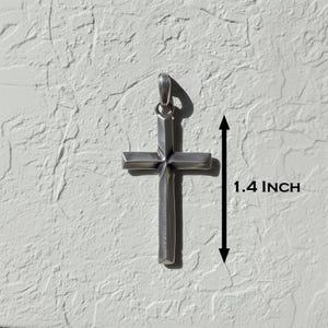 Puede incluir: Colgante plateado con forma de cruz. La cruz mide 3,5 cm de largo. El colgante tiene un lazo en la parte superior para una cadena. La cruz es un s&iacute;mbolo religioso.