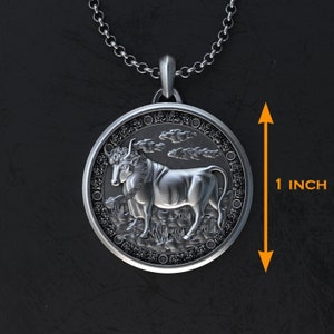 May include: Silver pendant necklace featuring a detailed bull design with a black and white finish. The pendant is 1 inch in diameter.