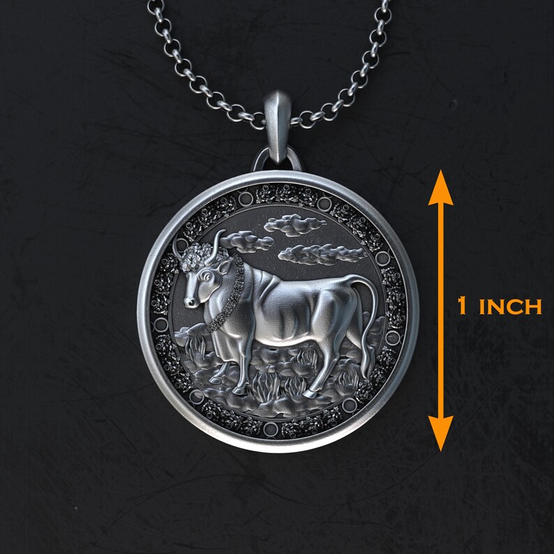 May include: Silver pendant necklace featuring a detailed bull design with a black and white finish. The pendant is 1 inch in diameter.
