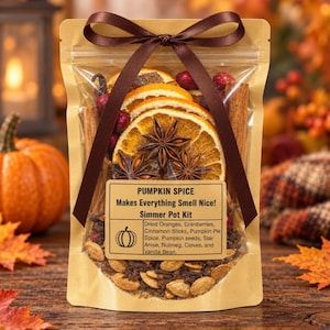 May include: A clear pouch containing a pumpkin spice simmer pot kit with dried orange slices, star anise, cinnamon sticks, cranberries, and pumpkin seeds. A brown ribbon is tied at the top. The label reads: PUMPKIN SPICE Makes Everything Smell Nice! Simmer Pot Kit. Dried Oranges, Cranberries, Cinnamon Sticks, Pumpkin Pie Spice, Pumpkin seeds, Star Anise, Nutmeg, Cloves, and Vanilla Bean.