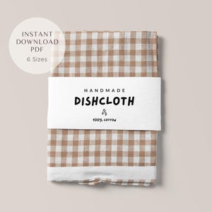 Puede incluir: Un paño de cocina doblado con un patrón de cuadros marrones y blancos, envuelto con una banda blanca. La banda dice "HANDMADE DISHCLOTH" y "100% COTTON". Un gráfico circular encima del paño de cocina dice "INSTANT DOWNLOAD PDF 6 Sizes".
