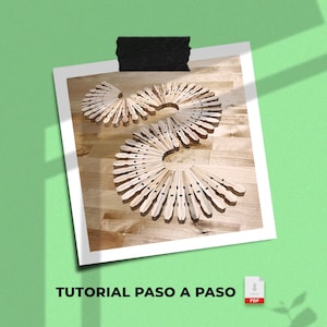 Puede incluir: Disposición de pinzas de madera en un patrón en espiral sobre una superficie de madera. Las pinzas están dispuestas en un diseño circular, creando un elemento decorativo. La imagen está sobre un fondo blanco con el texto "TUTORIAL PASO A PASO".