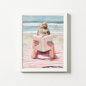 Puede incluir: Una pintura de una mujer leyendo un libro en una toalla de playa a rayas rosa y blanca. La mujer tiene el pelo rubio en un moño y lleva un traje de baño blanco. La playa está en el fondo.