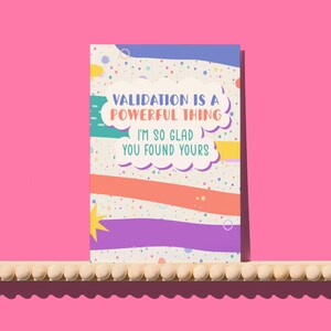Puede incluir: Una colorida tarjeta de felicitación con el texto "VALIDATION IS A POWERFUL THING I'M SO GLAD YOU FOUND YOURS." La tarjeta tiene un fondo blanco con rayas coloridas y confeti. Una estrella amarilla está en la esquina inferior izquierda.