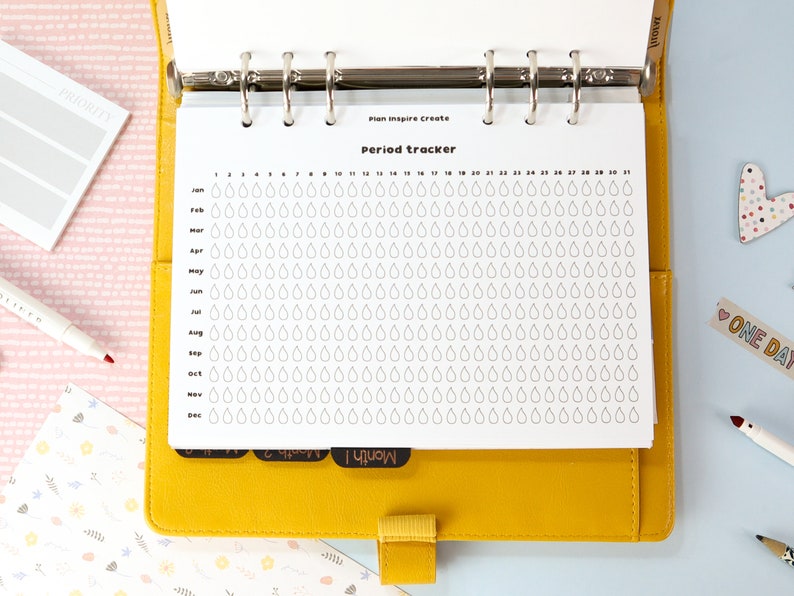 May include: A white period tracker page with a grid of raindrops for each day of the year. The page is labeled "Period Tracker" and is part of a planner.