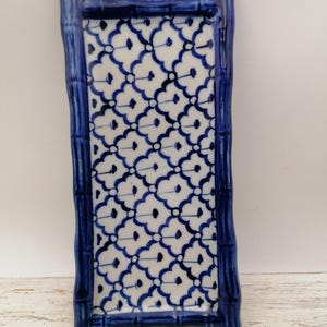 May include: A rectangular ceramic tray with a blue bamboo-style frame and a white and blue floral pattern. The tray has a raised edge and is designed for decorative or functional use. The overall design is reminiscent of traditional Asian pottery.