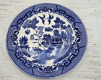Op de afbeelding: Een blauw en wit porseleinen bord met een traditioneel Chinees wilgenmotief. Het bord heeft een gegolfde rand en een verhoogde rand.