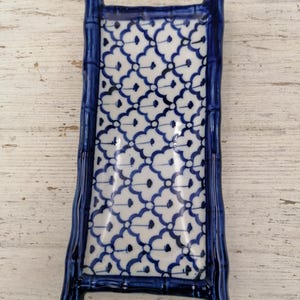 May include: Rectangular ceramic serving dish with a bamboo-style frame in glossy dark blue. The interior features a white background with a repeating blue floral pattern. Ideal for serving appetizers or small dishes.