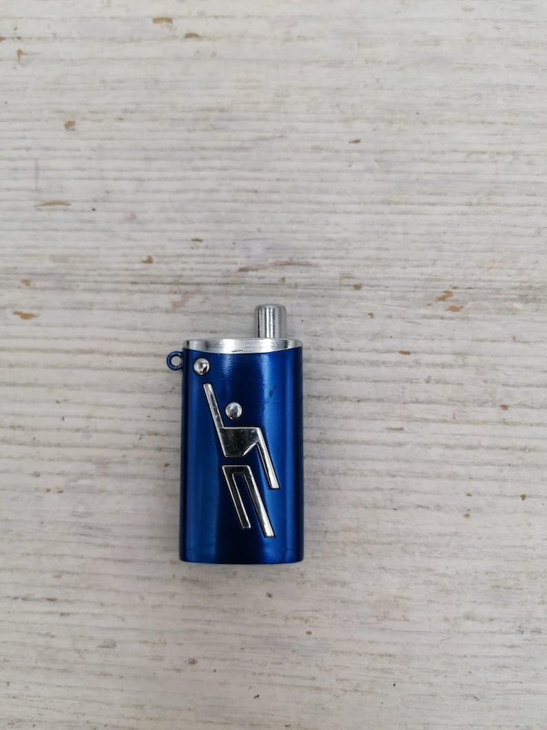 Puede incluir: Un llavero de metal azul con una figura plateada de una persona practicando un deporte. El llavero tiene una parte superior plateada y un anillo plateado.